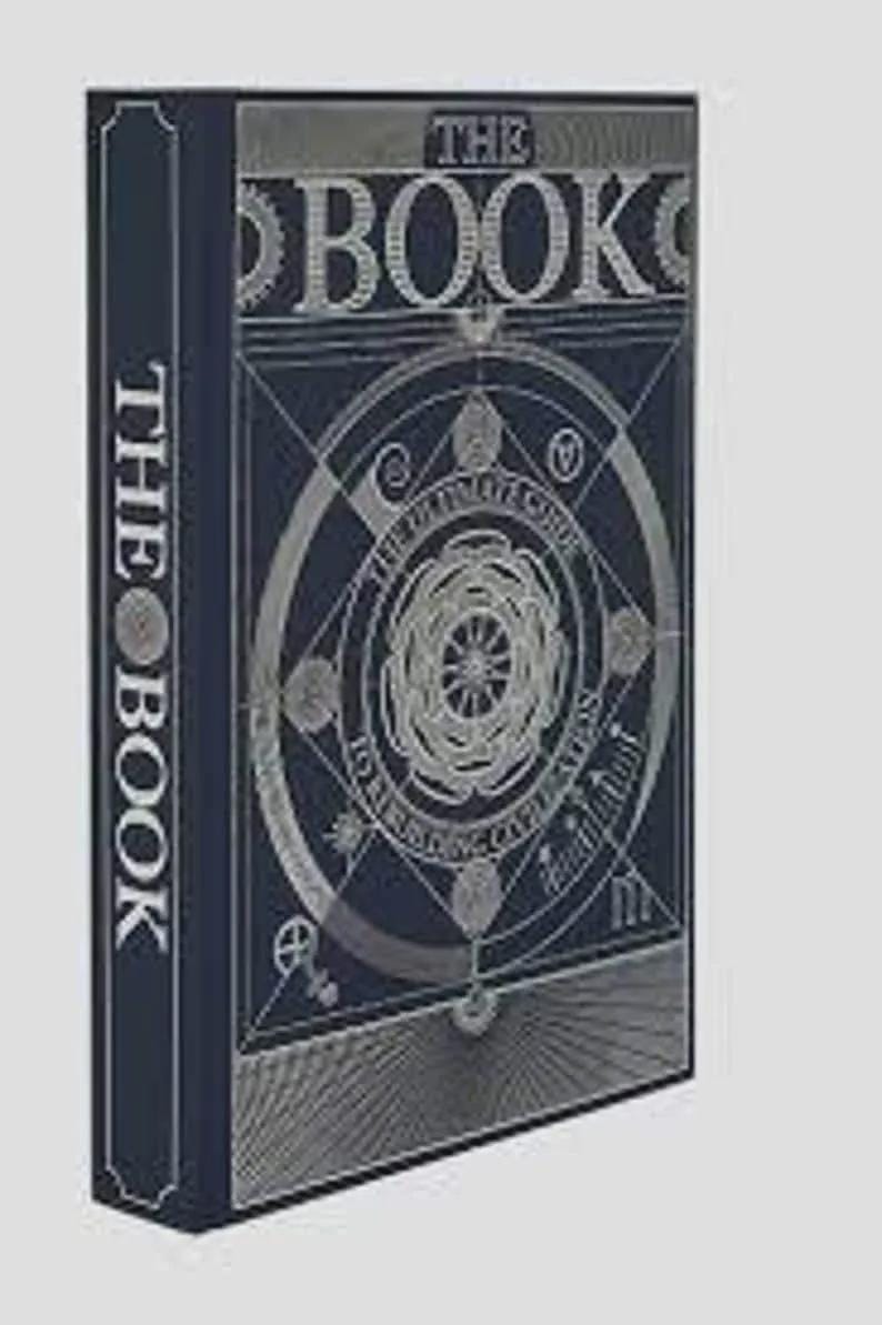 Może przedstawiać: Ciemnoniebieska książka w twardej oprawie ze srebrnymi zdobieniami na okładce i grzbiecie. Okładka zawiera napis THE BOOK oraz THE ULTIMATE GUIDE TO REBUILDING CIVILIZATION, otoczony geometrycznymi wzorami kołowymi i grafikami liniowymi.