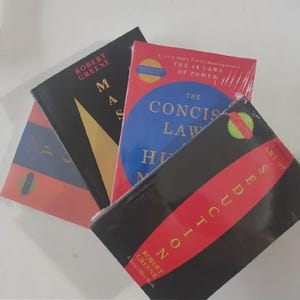 K&ouml;nnte beinhalten: Eine Sammlung von vier B&uuml;chern von Robert Greene, darunter The Concise Laws of Human Nature, Mastery und The Art of Seduction. Die B&uuml;cher haben schwarze, rote und blaue Einb&auml;nde mit wei&szlig;em und gelbem Text und sind in Klarsichtfolie verpackt.