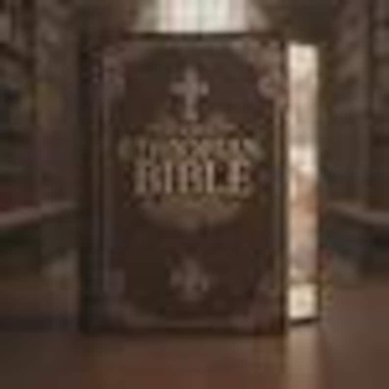 May include: A dark brown hardcover book titled ETHIOPIAN BIBLE in gold lettering on the front cover. The cover features an ornate, decorative border and a central cross symbol above the text. The book is standing upright with a visible spine.
