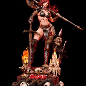 Może przedstawiać: Szczegółowa figurka kolekcjonerska Red Sonja przedstawiająca wojowniczkę z długimi rudymi włosami, w metalowej zbroi łuskowej, trzymającą wielki topór bojowy i miecz. Podstawa zawiera czaszki, węża, świece oraz tabliczkę z napisem Red Sonja.