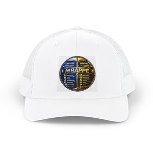 May include: A white trucker hat featuring a central graphic of a split blue and gold soccer ball. The text reads MBAPPÉ: THE STRIKER and MBAPPÉ: THE CHAMPION, with an acrostic design listing traits like Masterful, Bold, Acceleration, Precision, Powerful, Execution, Motivated, Brilliance, Agility, Pace, Pure, and Excellence.