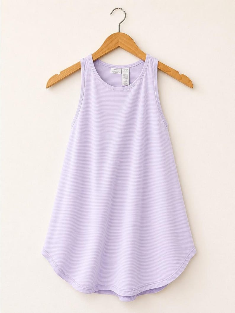 Peut inclure: Un d&eacute;bardeur sans manches violet clair avec un motif &agrave; fines rayures horizontales, une encolure ronde et un ourlet arrondi. Le v&ecirc;tement est pr&eacute;sent&eacute; sur un cintre en bois, r&eacute;v&eacute;lant une coupe simple avec une &eacute;tiquette de marque visible.