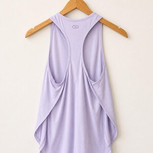 Peut inclure: Un d&eacute;bardeur dos nageur de couleur lavande clair avec une texture finement c&ocirc;tel&eacute;e &agrave; l'horizontale. Le v&ecirc;tement pr&eacute;sente un ourlet arrondi et un petit logo en forme de symbole infini imprim&eacute; en violet fonc&eacute; pr&egrave;s de l'encolure au dos.