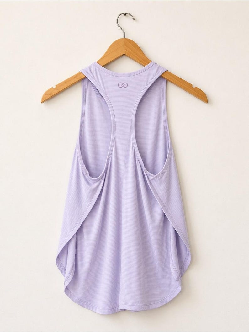 Peut inclure: Un d&eacute;bardeur dos nageur de couleur lavande clair avec une texture finement c&ocirc;tel&eacute;e &agrave; l'horizontale. Le v&ecirc;tement pr&eacute;sente un ourlet arrondi et un petit logo en forme de symbole infini imprim&eacute; en violet fonc&eacute; pr&egrave;s de l'encolure au dos.