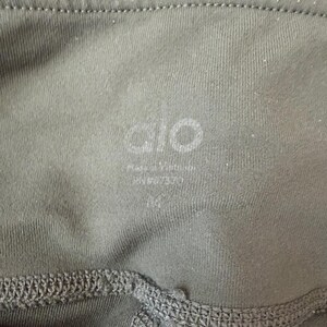 Peut inclure: Un legging vert olive dot&eacute; d'une taille haute avec le nom de la marque alo imprim&eacute; en blanc. Sous le nom de la marque, le texte indique Made in Vietnam, RN# 107370, et la taille M est clairement imprim&eacute;e &agrave; l'int&eacute;rieur du tissu.