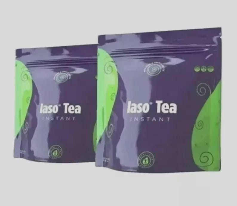 May include: Two purple and green pouches of Iaso Tea Instant. The packaging features the text Iaso Tea Instant in white, with swirling green graphic patterns on the sides and small circular logos printed on the front of each sealed bag.