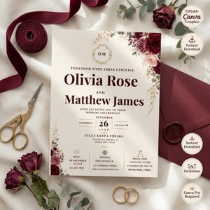 May include: A wedding invitation card featuring burgundy and blush floral accents, gold monogram, and dark red text. The card displays the names Olivia Rose and Matthew James, date December 26, 2026, and venue details. Includes a burgundy envelope and ribbon.