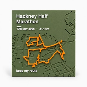 May include: A square olive green plaque featuring a raised white map of the Hackney Half Marathon route. The text reads Hackney Half Marathon, 17th May 2026, 21.4 km, and keep my route. A bright orange line traces the marathon path across the map.