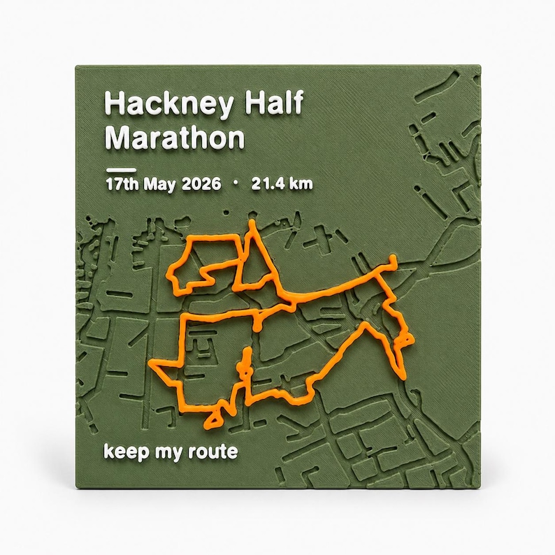 May include: A square olive green plaque featuring a raised white map of the Hackney Half Marathon route. The text reads Hackney Half Marathon, 17th May 2026, 21.4 km, and keep my route. A bright orange line traces the marathon path across the map.