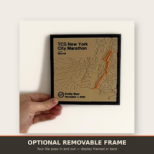 May include: A square wall plaque featuring a tan 3D relief map of the TCS New York City Marathon route with an orange path line. The text reads TCS New York City Marathon 26.2 mi, Emily Burr, and November 1, 2026, all encased in a black frame.