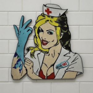 May include: A flat, die-cut graphic patch featuring a blonde nurse with a red cross on a white cap, wearing a white uniform with a red top underneath. The nurse wears a blue glove on one hand and has a name tag that reads Blink-182.