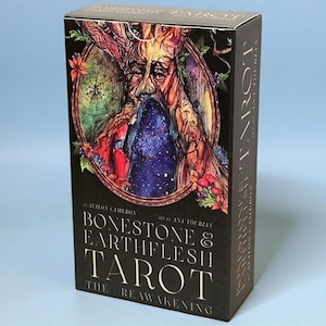 May include: A rectangular tarot deck box titled Bonestone & Earthflesh Tarot: The Reawakening by Avalon Cameron and Ana Tourian. The front features a detailed illustration of a tree-like face with a cosmic, starry void inside a circular frame.