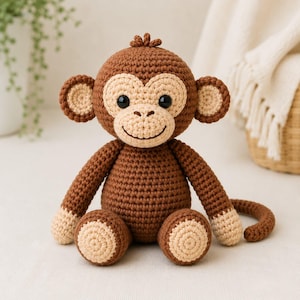 May include: A brown and beige crocheted monkey stuffed toy with a round head, large ears, black plastic eyes, and a stitched smile. The monkey has a dark brown body, light beige face, hands, and feet, and a long, curved tail extending to the side.