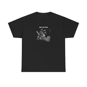 May include: A black short-sleeved t-shirt featuring a graphic print of a hooded figure holding a sword and a shield, facing three small spiky creatures. Above the graphic, the text reads ONE LAST BUG, accompanied by binary code and programming symbols.