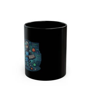 May include: A solid black ceramic mug featuring a colourful graphic of a hooded character in blue armour holding a keyboard. The illustration includes floating code snippets, small round creatures, and a coffee cup against a dark digital background.