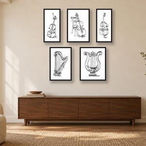May include: A set of five framed wall art prints featuring black and white line drawings of musical instruments, including a cello, a double bass, a harp, and a lyre, arranged in a gallery display on a plain wall above a wooden console.