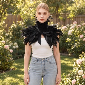 May include: A black feather collar featuring a high neck design and a satin ribbon tie at the front. The accessory is layered with dark, textured feathers that extend over the shoulders and neck, creating a structured, voluminous appearance.
