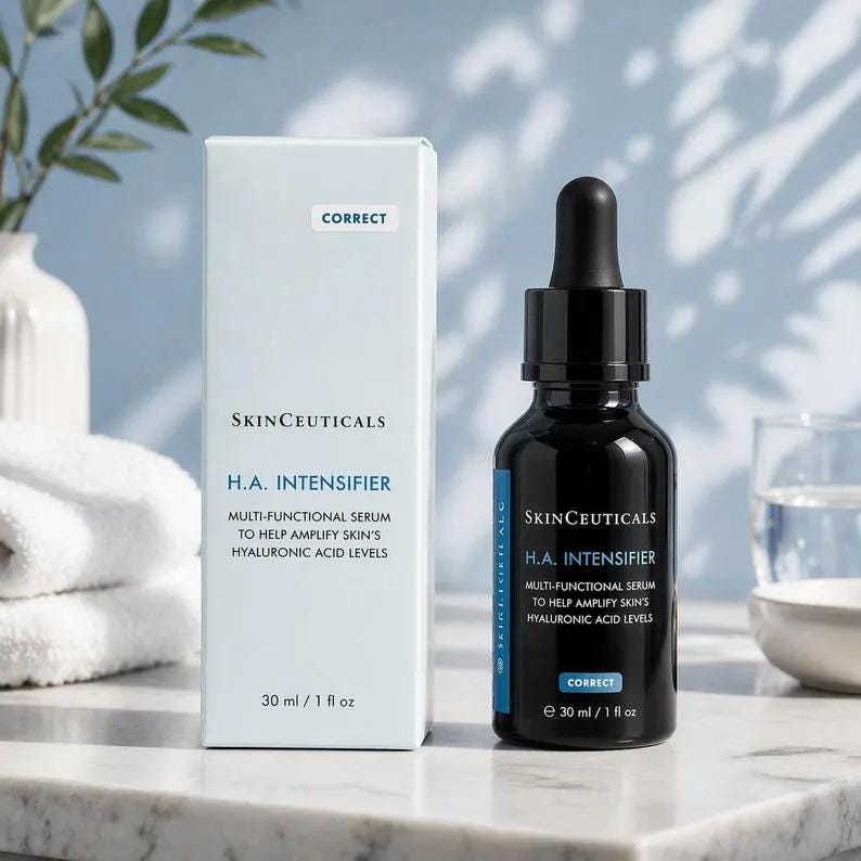 May include: A SkinCeuticals H.A. Intensifier multi-functional serum bottle and its matching light blue box. The black glass dropper bottle and box both feature the text SkinCeuticals H.A. Intensifier, 30 ml / 1 fl oz, and Correct. The set is displayed upright.