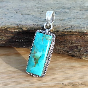 May include: A rectangular pendant featuring a vibrant turquoise stone with brown matrix veins, set in a polished silver frame with a twisted rope border and a smooth silver bail at the top. The text Boho Mystic Silver is visible at the bottom right.