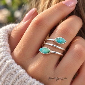 May include: A silver bypass ring featuring two marquise-cut turquoise stones with natural brown veining. The band wraps around the finger in a spiral design. The text "Boho Mystic Silver" is printed in the bottom right corner of the image.