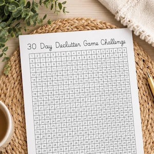 May include: A white paper sheet featuring a 30 Day Declutter Game Challenge grid with black lines and numbers from 1 to 30 printed in each square. The document is oriented vertically and contains a clear, bold title at the top of the page.
