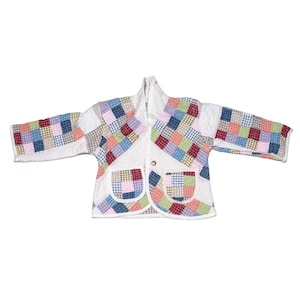 May include: A quilted jacket with a patchwork design. The jacket features a white base with colorful square patches in shades of blue, pink, green, and red. It has two front pockets and a single button closure. The sleeves are long and the collar is a shawl style.
