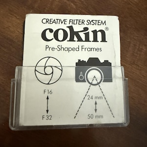 May include: A Cokin Creative Filter System Pre-Shaped Frames insert card inside a clear plastic sleeve. The white card features black text and graphics, including a camera icon, aperture symbols, and labels for F16, F32, 24 mm, and 50 mm.