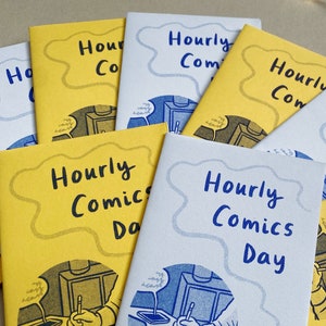 A collection of mini zines called Hourly Comics Day, some printed on yellow paper and some on lilac, spread out on a grey background.