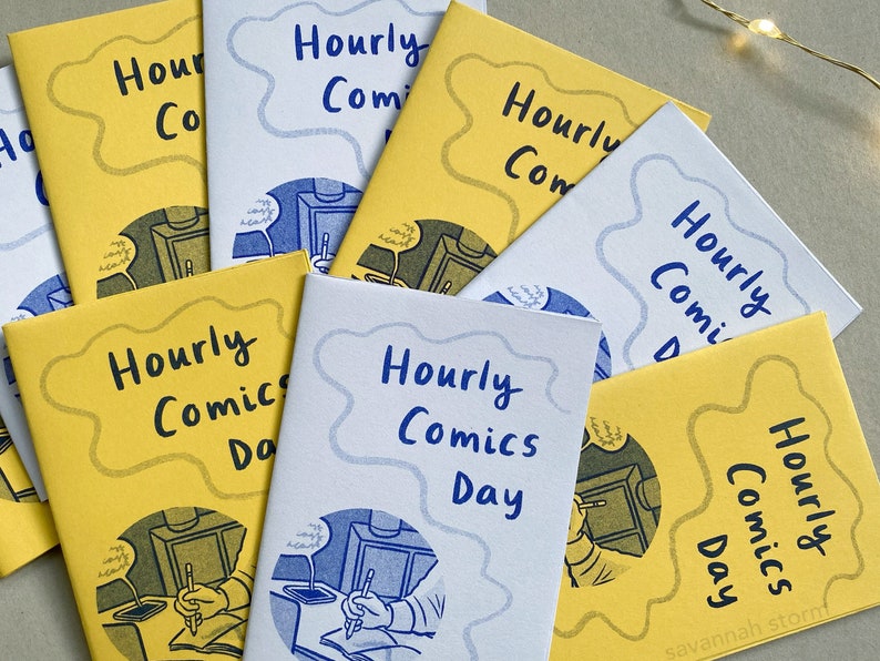 A collection of mini zines called Hourly Comics Day, some printed on yellow paper and some on lilac, spread out on a grey background.