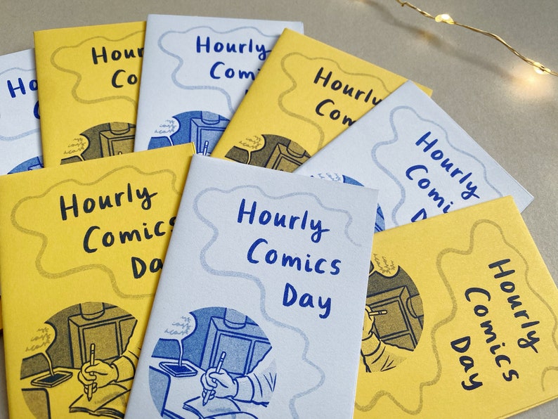 A collection of mini zines called Hourly Comics Day, some printed on yellow paper and some on lilac, spread out on a grey background.