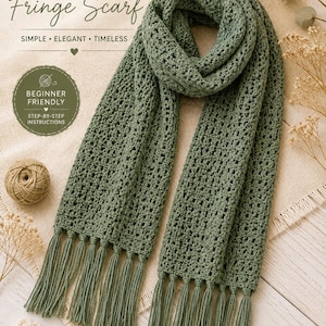 Op de afbeelding: Een saliegroene gehaakte sjaal met een herhalend gestructureerd steekpatroon en lange franjes aan beide uiteinden. De tekst luidt: CROCHET PATTERN, Classic Fringe Scarf, SIMPLE ELEGANT TIMLESS, BEGINNER FRIENDLY, STEP-BY-STEP INSTRUCTIONS, TheWorldsEmporium, MADE WITH LOVE, BEAUTIFUL TEXTURE, SOFT & COZY, PERFECT FOR EVERY SEASON.