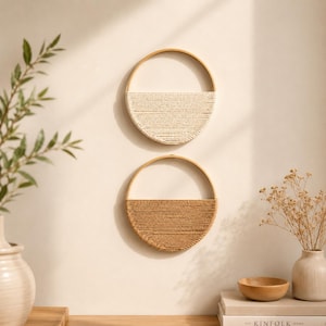 May include: Two circular wall hangings featuring a wooden hoop frame. The top piece has a cream-colored cord wrapped in a semi-circle pattern, while the bottom piece features a tan-colored cord wrapped in the same semi-circular design.