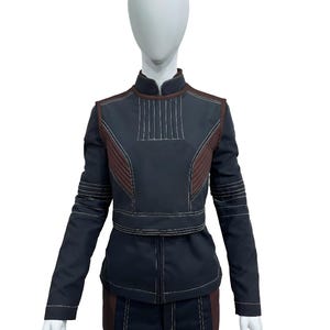 May include: A dark navy blue long-sleeved jacket and matching trousers set featuring a high collar, brown side panels, and prominent white topstitching. The jacket includes a structured chest panel with vertical stitching and horizontal sleeve details.
