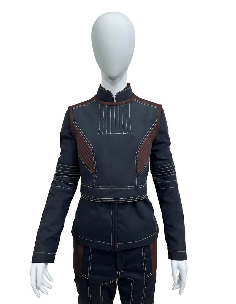 May include: A dark navy blue long-sleeved jacket and matching trousers set featuring a high collar, brown side panels, and prominent white topstitching. The jacket includes a structured chest panel with vertical stitching and horizontal sleeve details.