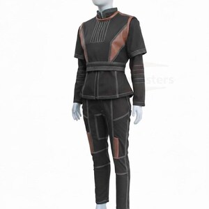 May include: A black two-piece outfit consisting of a high-neck top with brown textured panels and a matching pair of trousers. The ensemble features prominent white topstitching throughout, a structured waist belt, and brown accents on the shoulders and legs.