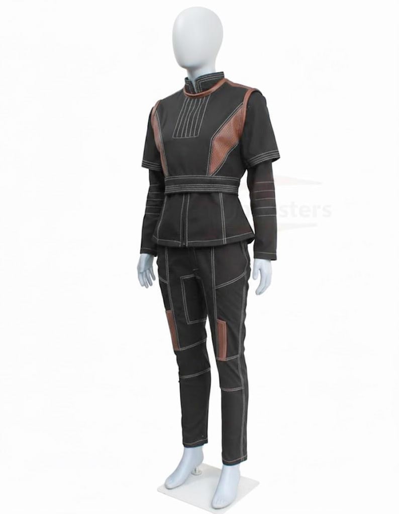 May include: A black two-piece outfit consisting of a high-neck top with brown textured panels and a matching pair of trousers. The ensemble features prominent white topstitching throughout, a structured waist belt, and brown accents on the shoulders and legs.