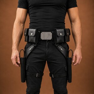 May include: A black utility belt featuring a central metallic buckle with geometric detailing, four attached pouches with snap closures, and two vertical holsters extending down the thighs, secured by adjustable leg straps with metal buckles.
