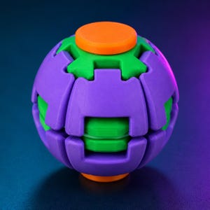 May include: A spherical puzzle toy featuring interlocking purple and green plastic segments. The object has a smooth, bright orange circular button at the top and bottom, with a complex geometric structure of alternating colored panels.