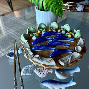 A 26 piece set of decorative chopstick holders. A variety of 18 fun fish, colorful pillows and lovely ceramic designs. Fun and festive.