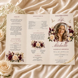 May include: A tri-fold funeral program featuring a portrait of a woman surrounded by burgundy and cream roses. The text includes Celebrating the Life of Michelle Danielle Simmons, May 14, 1978 – August 23, 2025, with sections for obituary, order of service, and acknowledgments.