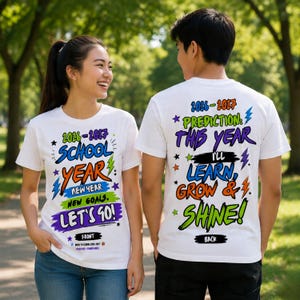 May include: A white t-shirt featuring a colorful graphic design. The front displays the text 2026-2027 SCHOOL YEAR NEW YEAR. NEW GOALS. LET'S GO! The back displays 2026-2027 PREDICTION: THIS YEAR I'LL LEARN, GROW & SHINE! with star and lightning bolt icons.