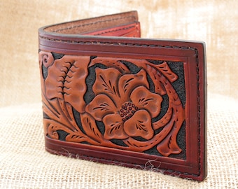 May include: A brown leather wallet with a floral design embossed on the front. The design features a large flower with intricate details and leaves.
