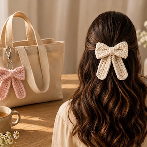 May include: A cream-colored crochet bow hair clip and a matching light pink crochet bow keychain attached to a beige canvas tote bag. The hair clip is secured in long brown hair, while the keychain hangs from the handle of the fabric bag.