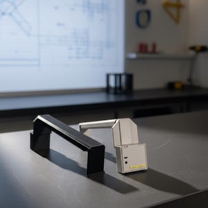May include: A black and a white angular handle-shaped device, with the white unit featuring a small black sensor and the yellow text "FibrePulse" printed on the front face. Both objects have a geometric, bridge-like structure with flat surfaces.