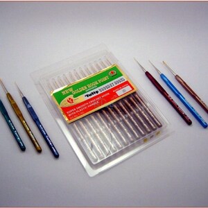 May include: A pack of 10 gold crochet hooks with plastic handles. The hooks are in a clear plastic package with a green and red label that says "New Golden Book Point Tulip Crochet Hook". There are also three individual crochet hooks in green, gold, and blue.