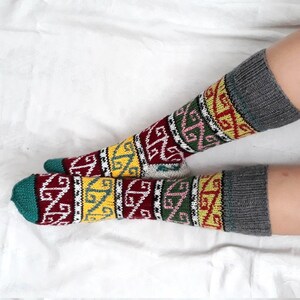 May include: A pair of colorful socks with a geometric pattern in shades of red, yellow, green, and white. The socks have a gray cuff.