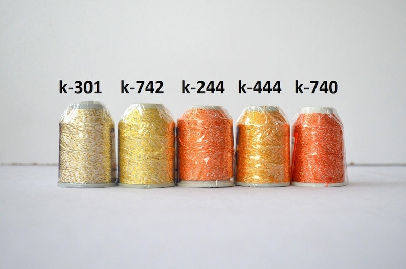 May include: Five spools of metallic thread in various colors, including gold, silver, and orange. The spools are labeled with the following codes: k-301, k-742, k-244, k-444, and k-740.