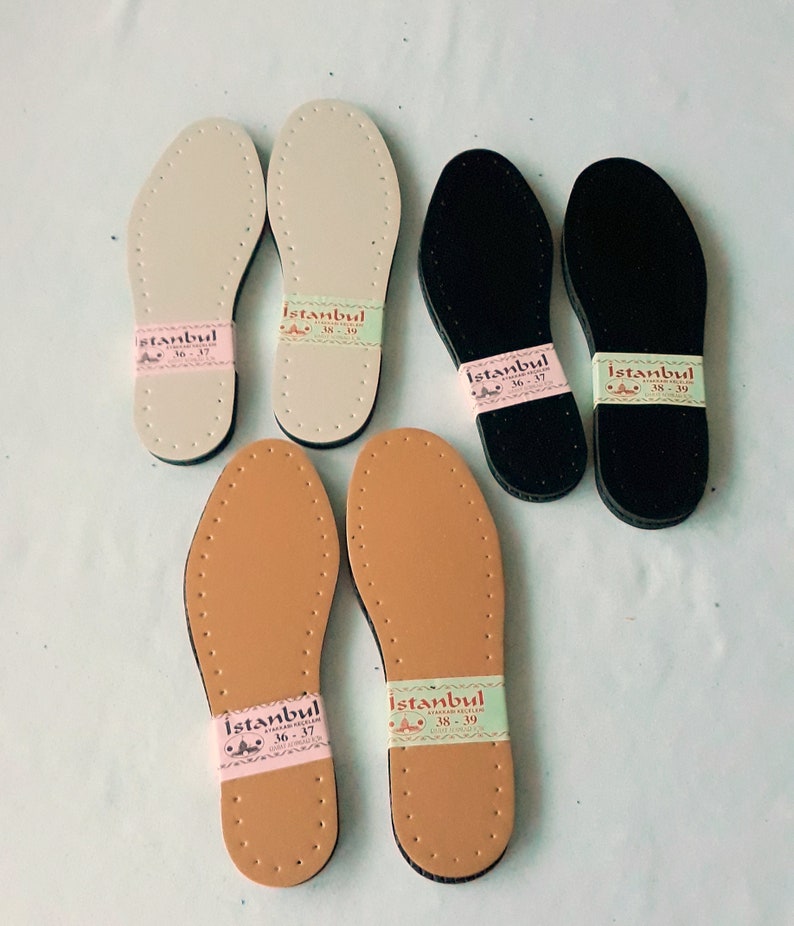 May include: Four pairs of leather shoe soles in different sizes and colors. The soles are beige, brown, and black. Each sole has a label with the word "Istanbul" and size numbers.