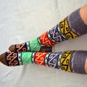 May include: A pair of colorful knee-high socks with a geometric pattern in shades of red, blue, green, yellow, and brown. The socks are knitted and have a gray cuff.
