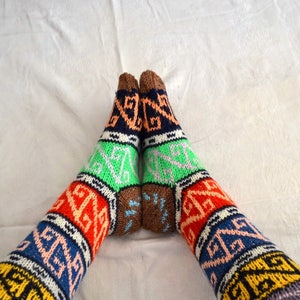 May include: A pair of colorful knitted socks with geometric patterns in shades of blue, green, orange, red, brown, and white.